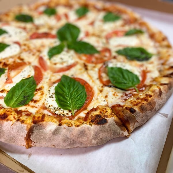 Via Capri Pizzeria's Margherita pizza with fresh basil, mozzarella, and tomatoes in a box.