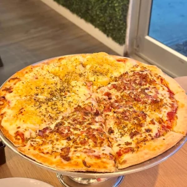 A large Via Capri Pizzeria pizza with two different toppings, one half cheese and the other meat.