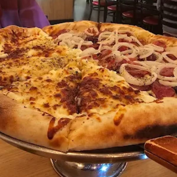 A large Via Capri Pizzeria pizza, half cheese and half pepperoni and onion, on a metal stand.