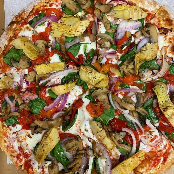 Via Capri Pizzeria's vibrant vegetarian pizza with artichokes, mushrooms, spinach, red onion, and peppers.