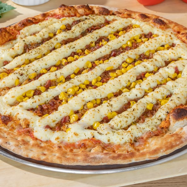 Via Capri Pizzeria's pizza with corn, bacon, and cheese stripes, garnished with herbs.